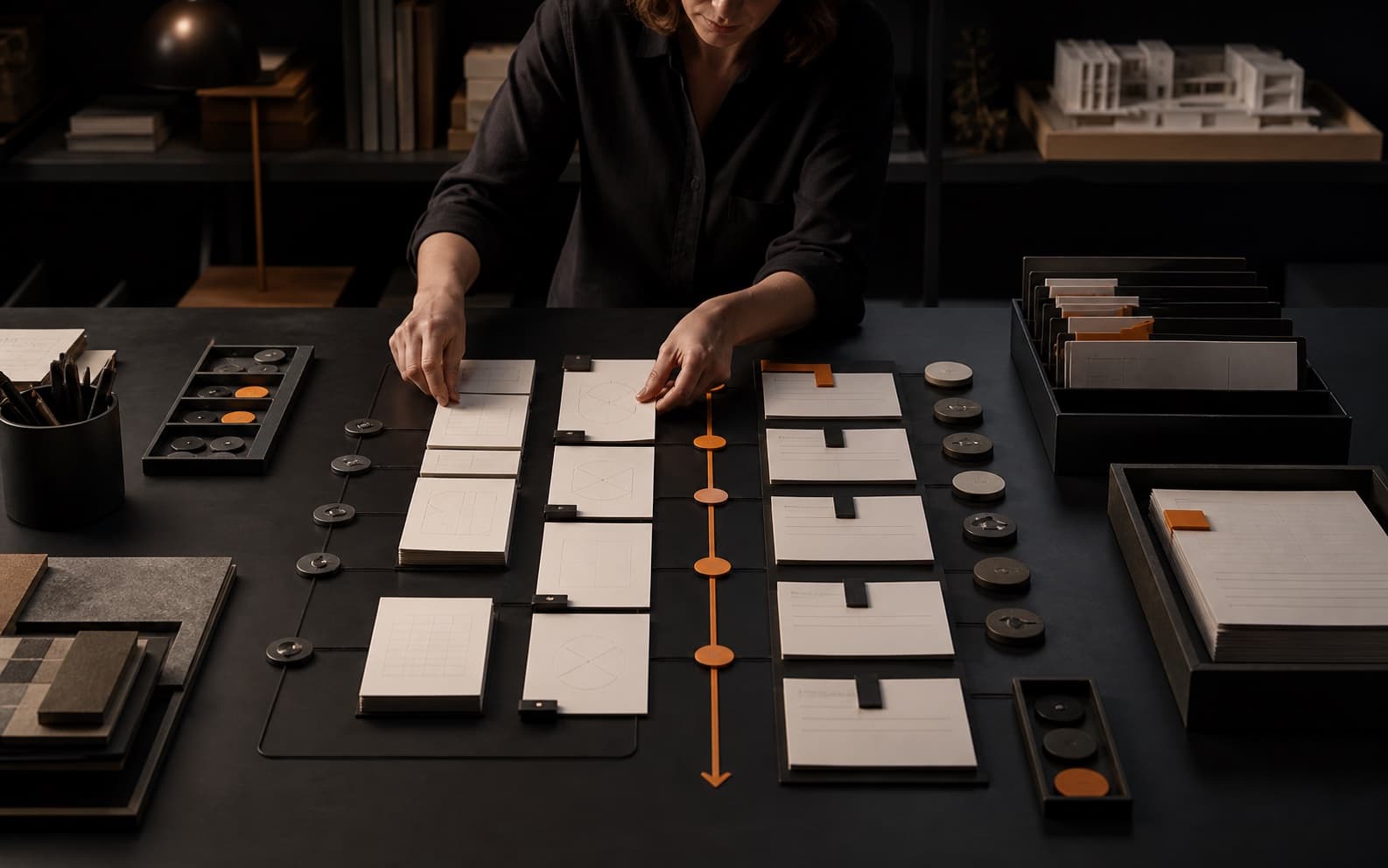 Operations lead arranging layered blank knowledge cards, ownership markers, review tokens, archival trays, and an orange retrieval path across a dark graphite studio table.