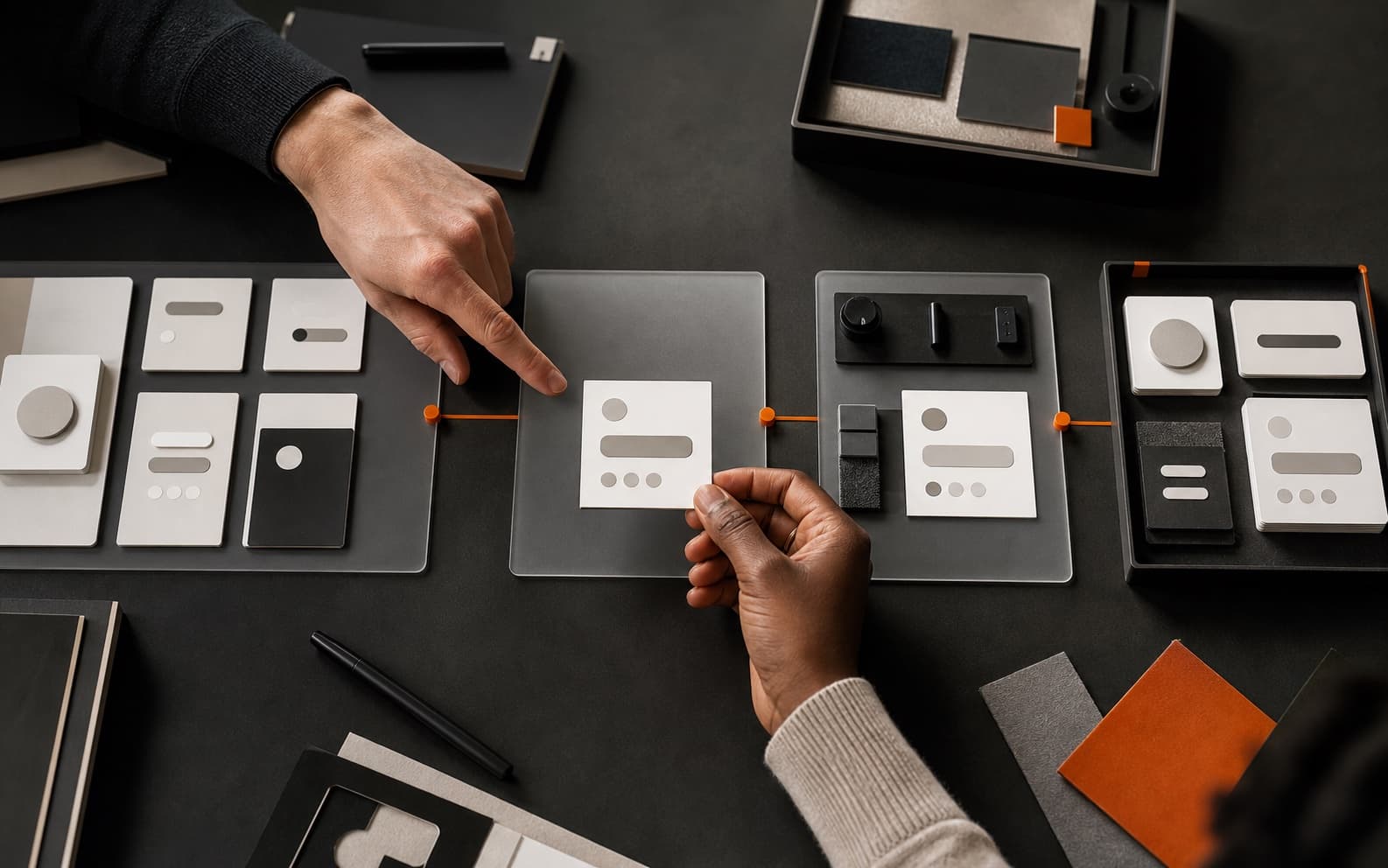 Top-down editorial scene of two designers reviewing an interface component across connected specification, testing, and reusable-library stations.