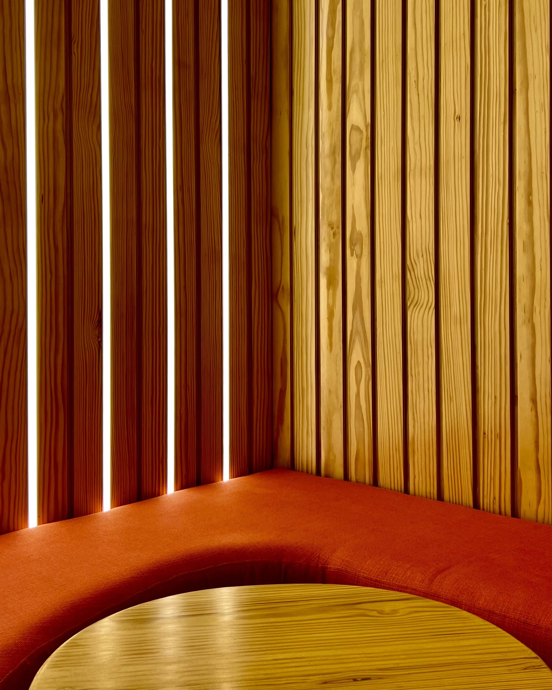 Completed Kurtos timber wall and orange upholstery detail with vertical linear lighting.
